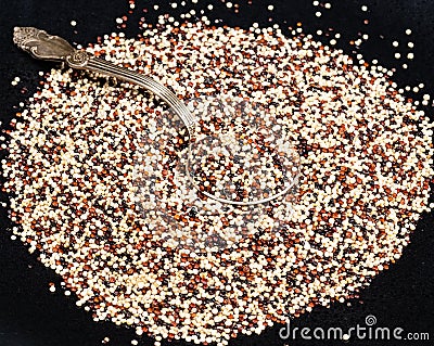 Tablespoon in mix of quinoa seeds on black Stock Photo