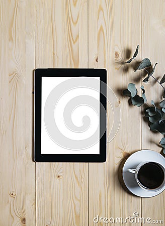 Tablet with a clean blank screen mockup monitor with a branch of eucalyptus and a cup of coffee on a wooden background Stock Photo