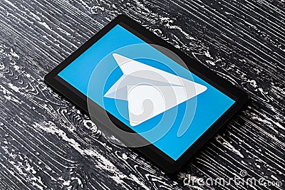 Tablet computer on a black wooden table with a messenger telegram logo on the screen Editorial Stock Photo