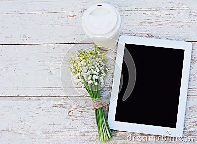 Tablet computer, a glass of coffee and lilies of valley Stock Photo