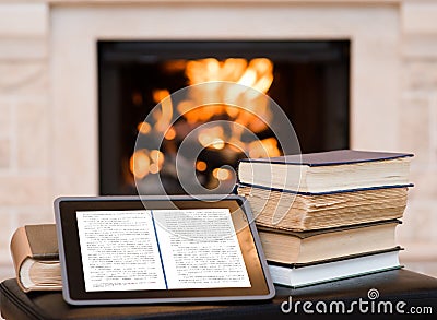 Tablet computer and pile books on the background of the fireplace Stock Photo