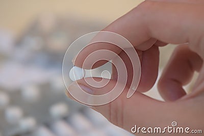 Tablet held between two fingers in front of defocused packagings Stock Photo