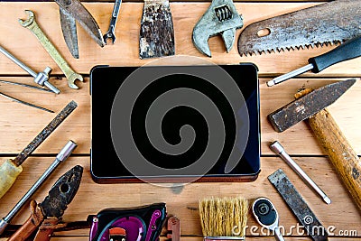 Tablet and old tools on a natural wooden background. Stock Photo