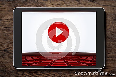 Tablet pc on wooden table with cinema screen displayed. Stock Photo