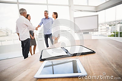 Tablet and planner in front of handshaking business people Stock Photo