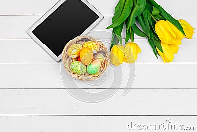 Tablet screen for message and colorful tulips and easter eggs on wooden background Stock Photo