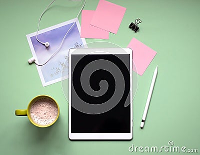 Tablet with a stylus on a green background.A Cup of coffee, headphones, photo Stock Photo