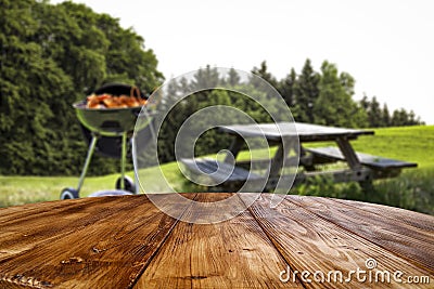Tabletop and blurred grill on grass and garden background. Stock Photo