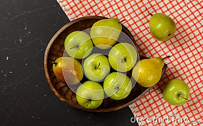 Tabletop photo wood carved bowl with apples and pears, red chequered tablecloth on black board Stock Photo
