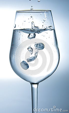 Tablets falling into the water. Backlight. White blue tone. Stock Photo