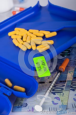 Tablets on a manual pill counter with please pay levy sticker Stock Photo