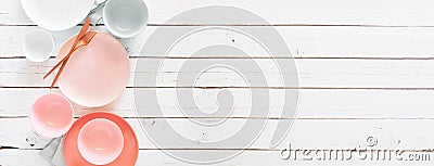 Tableware set in pTableware set in pastel pink, grey, coral and white colors. Top view, side border on a white wood banner backgro Stock Photo