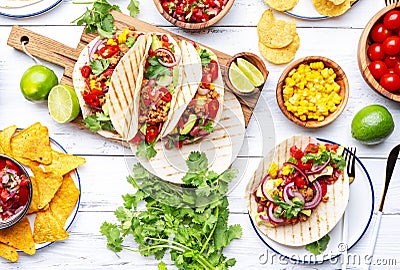 Taco party. Served table with tortillas, nachos, sauces, appetizers and plates. Homemade mexican food cooking scene. White table Stock Photo