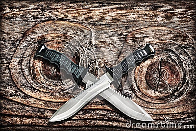 Tactical Combat Hunting Survival Bowie Knives With Crossed Blades On Grunge Vignetted Old Knotted Pinewood Grunge Background Stock Photo