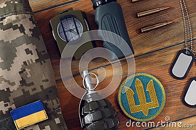 Tactical gear, military uniform and Ukrainian army patches on wooden table, flat lay Stock Photo