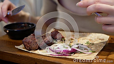 Tagliare le mani della donna con coltello e forchetta tagliando carne in un piatto sul tavolo in un ristorante stock footage Tagliare le mani della donna con coltello e forchetta tagliando carne in un piatto sul tavolo in un ristorante stock footage