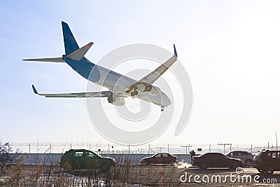 Tail view of landing airplane. Aircraft flying over highway. Road with high traffic near airport runway. Type of transport compar Stock Photo