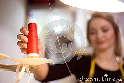 Tailor laboring at working place in atelier. Sewing machine, ruler, scissors, table lamp, threads on background. Stock Photo