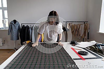 Tailor measure cloth fabric in studio. Young female designer create clothes in workshop atelier room Stock Photo