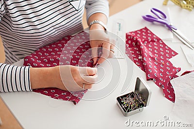 Young woman seamstress making pattern on fabric with tailors chalk. Girl working with a sewing pattern. Hobby sewing as a small bu Stock Photo