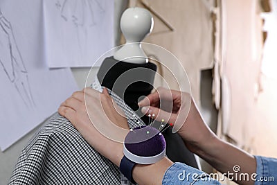 Tailor pinning fabric at mannequin in atelier, closeup Stock Photo