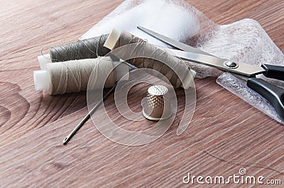 The tailor`s desk. Old sewing wooden drums or skeins on an old wooden worktable with scissors. Stock Photo