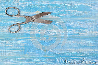 Tailor`s scissors on a blue wooden table. Stock Photo