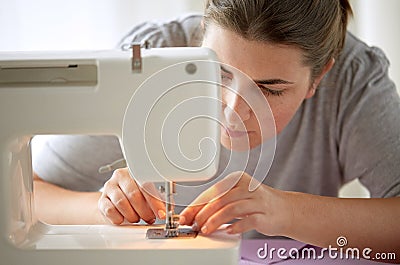 Tailor woman threading needle of sewing machine Stock Photo