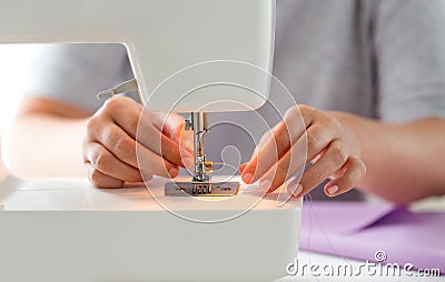 Tailor woman threading needle of sewing machine Stock Photo