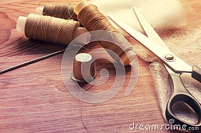 The tailor& x27;s desk. Old sewing wooden drums or skeins on an old wooden worktable with scissors. Toning for antiquity Stock Photo