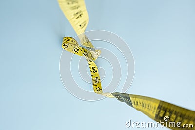 Tailors meter is hanging down, on a blue background. Measuring tape for sewing. Flatley. Stock Photo