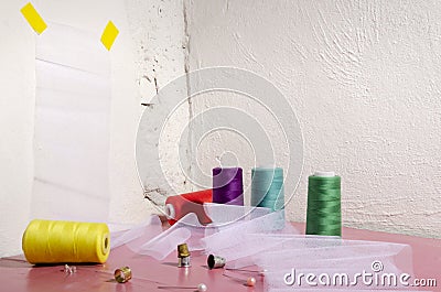 Vertical image. Different colorful spools of thread, white fabric, elastic, zippers on the pink background Stock Photo