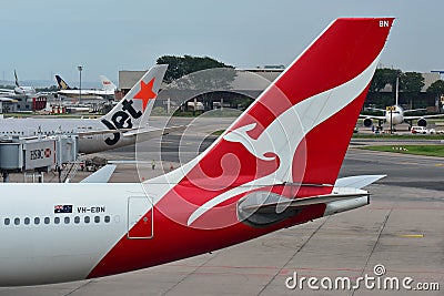 Tails of Jetstar International and Qantas aircraft belonging to the same family at Changi Airport Editorial Stock Photo