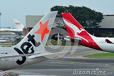 Tails of Jetstar International and Qantas aircraft belonging to the same family at Changi Airport Editorial Stock Photo