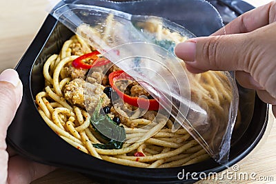 Take-away food ready meal: Woman hands holding open cling wrap a Stock Photo