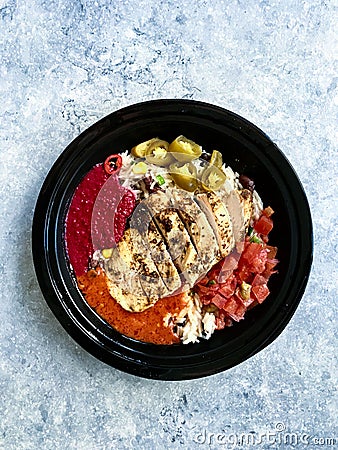 Take Away Jamaican Food Bowl with Chicken, Red Kidney Beans, Beet Sauce, Basmati Rice Pilaf, Avocado Guacamole, Jalapeno Pepper Stock Photo