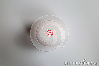 Take it easy and keep it simple concept: icon of red happy smiling face on isolated egg with with white background Stock Photo