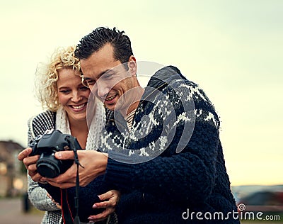 Take a look at this photograph. a young couple looking at photos while on vacation. Stock Photo