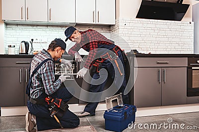 Take a pleasure from success. Two men technician sitting near dishwasher Stock Photo