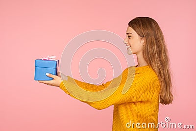 Take it! Portrait of charming generous red hair woman in sweater giving small gift box to the side and smiling, offering holiday Stock Photo
