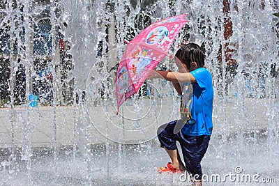 take red umbrel girl playing by water fountain Editorial Stock Photo