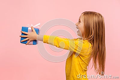 Take it! Side view of generous kind adorable little girl giving present and congratulating on birthday, mother`s day Stock Photo