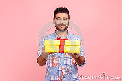 Take it! Young adult happy man wearing blue casual style shirt giving gift box to camera with excited smile, greeting on holiday Stock Photo