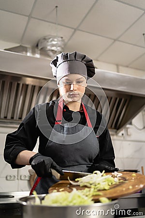 takeaway food in the restaurant. woman chef in special clothes in the kitchen prepares cabbage salad. Food delivery. Stock Photo