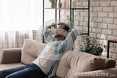 Peaceful young man recline on sofa breath deep enjoy nap Stock Photo