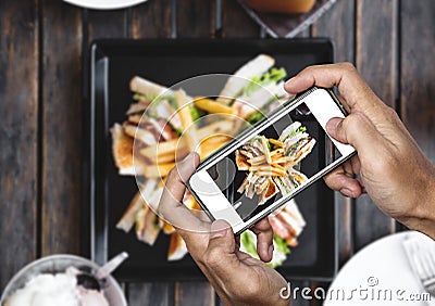 Taking food photo, food photography by smart phone, club sandwich with french fries on wooden table Stock Photo