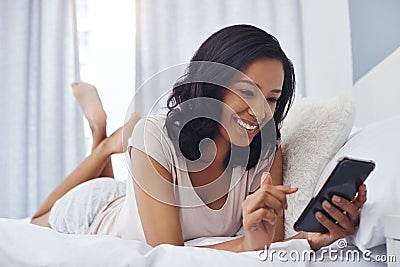 Taking her social media roll call. a young woman waking up in the morning and using her phone in bed. Stock Photo