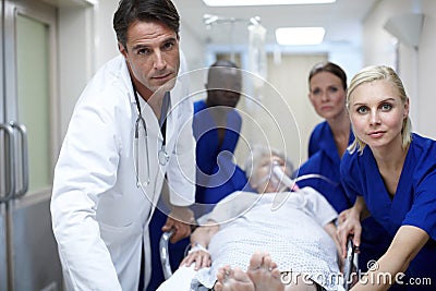 Taking her to the OR. Portrait of a group of doctors pushing a patient down the hall. Stock Photo