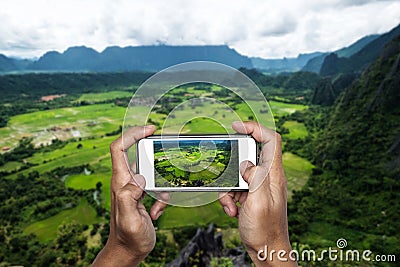 Taking nature landscape photo by smart phone on mountain peak, traveling in tropical country Stock Photo