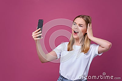 Taking picture. cheerful blond-haired woman doing selfie on isolated pink background Stock Photo